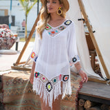 Femme portant une tunique de plage bohème blanche en crochet avec franges colorées et un chapeau de paille