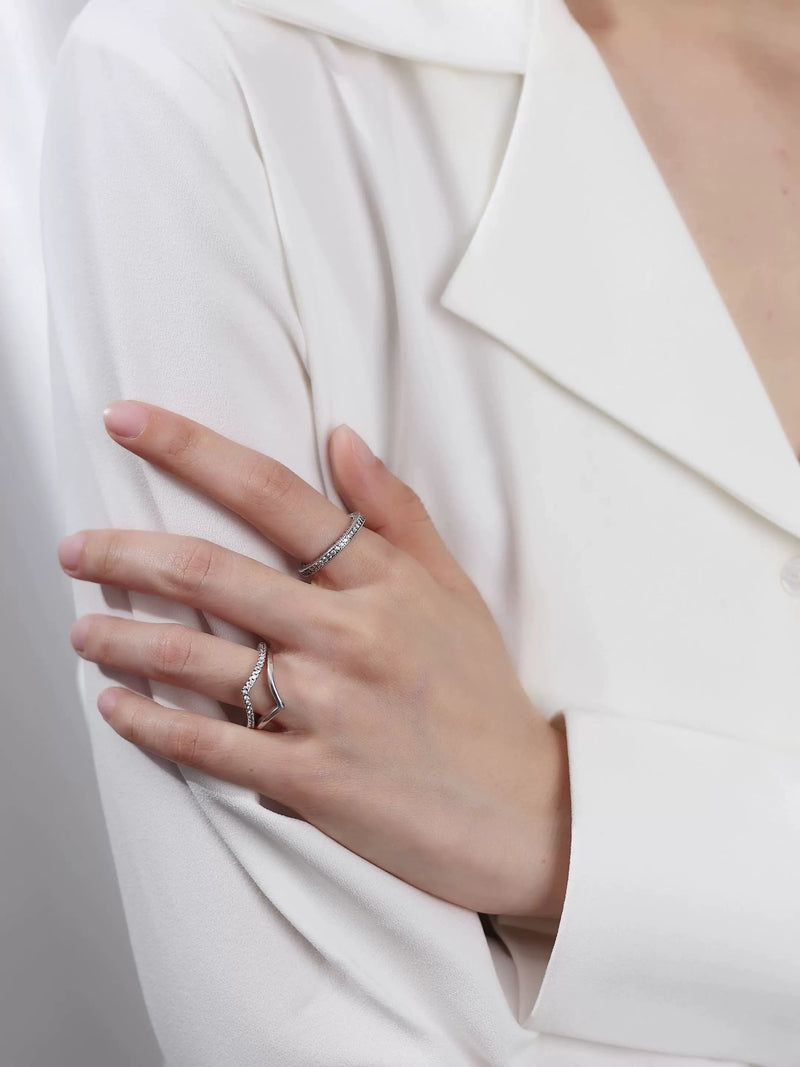 Femme portant deux bagues en argent 925 ornées de zircons sur fond blanc, style minimaliste et élégant