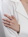 Femme portant deux bagues en argent 925 ornées de zircons sur fond blanc, style minimaliste et élégant