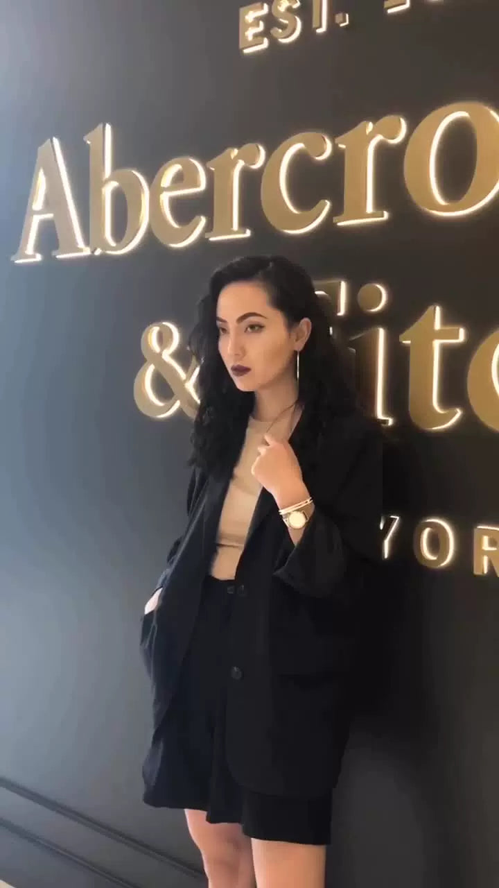 Femme portant une montre Hannah Martin dorée avec un tailleur noir, style élégant et professionnel