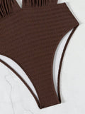 Gros plan sur la texture gaufrée et la coupe haute du maillot de bain brun