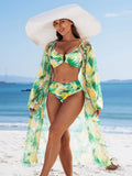 Femme en maillot de bain 3 pièces imprimé vert et jaune, posant avec élégance sur la plage