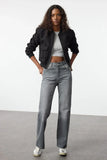 Femme portant un jean vintage taille haute évasé en coton avec un bomber noir et un top gris.