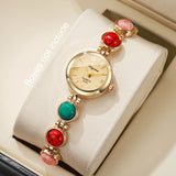 Montre femme bracelet perles colorées avec cadran doré, posée sur un coussin, sans boîte