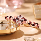 Montre femme dorée rose avec bracelet géométrique sur une surface miroir, ambiance glamour