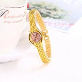 Montre bracelet femme dorée avec cadran rose clair sur fond blanc et motifs floraux