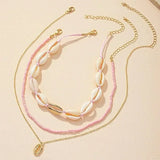 Ensemble de deux colliers fantaisie, un ras-du-cou perles roses et coquillages, l'autre chaîne fine avec pendentif coquillage doré