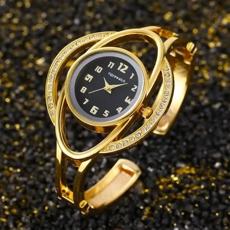 Montre bracelet femme dorée avec cadran noir et strass, vue de face sur fond noir pailleté