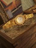 Montre quartz dorée pour femme avec cadran nacre et strass sur un fond artistique