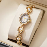 Montre bracelet dorée pour femme avec perles et strass sur fond crème