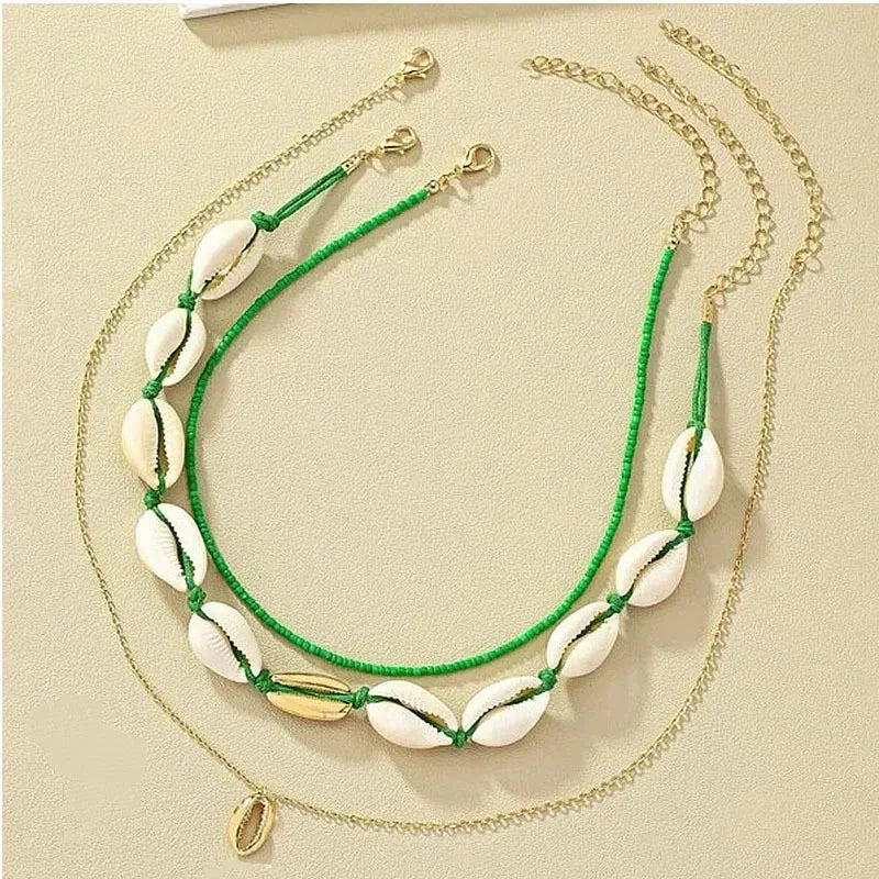 Ensemble de deux colliers fantaisie, un ras-du-cou perles vertes et coquillages, l'autre chaîne fine avec pendentif coquillage doré