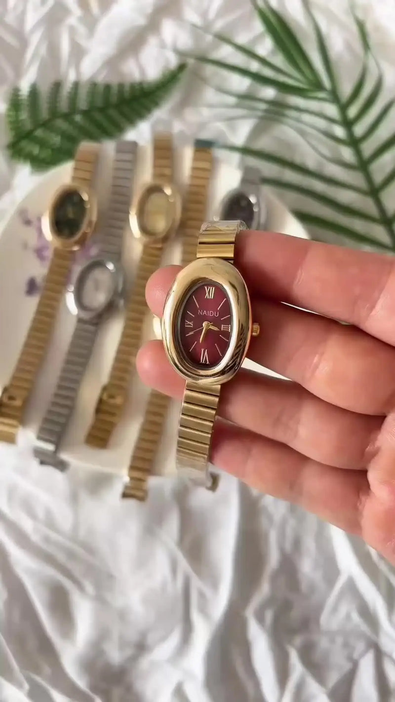 Montre quartz femme dorée et rouge, bracelet acier inoxydable sur plateau