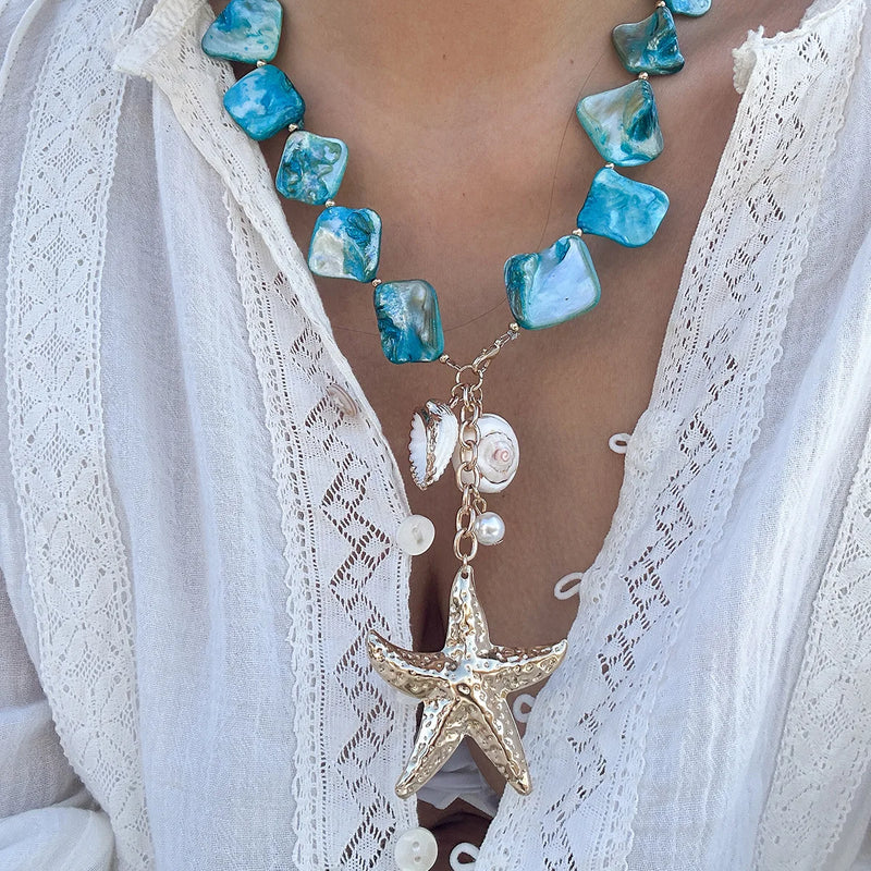 Collier bohème avec pendentif étoile de mer et perles bleues sur une chemise blanche en dentelle