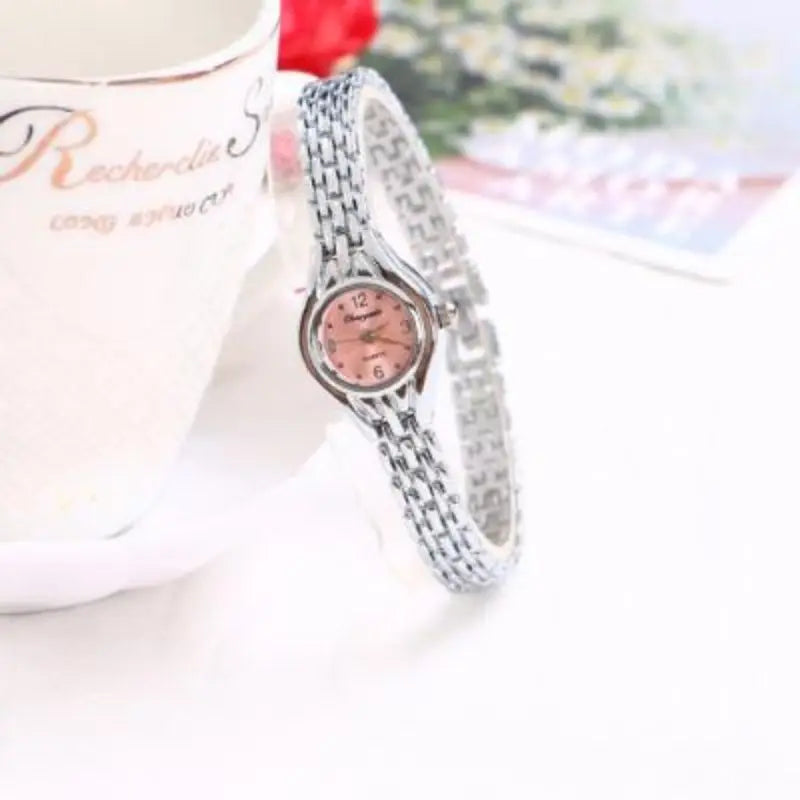 Montre bracelet femme argentée avec cadran rose clair sur fond blanc et motifs floraux