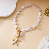 Collier ras du cou perles et coquillages posé sur fond beige avec décorations marines