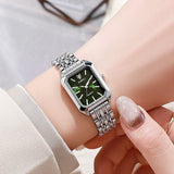 Montre femme carrée argentée avec cadran vert portée au poignet