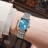 Montre carrée argentée avec cadran bleu clair portée au poignet d'une femme, éclat moderne.