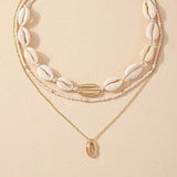 Collier ras-du-cou perles blanches avec pendentif coquille dorée, idéal pour l'été
