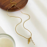 Collier doré avec pendentifs coquillage et perles multiples sur fond blanc