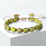 Bracelet bohème perles pierre impériale vert tressé main sur fond blanc