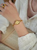 Femme portant une montre dorée rétro au poignet, détail du bracelet