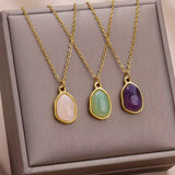 Gros plan d'un collier doré avec pendentif ovale en pierre jade verte