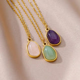 Gros plan d'un collier doré avec pendentif ovale en pierre améthyste violette