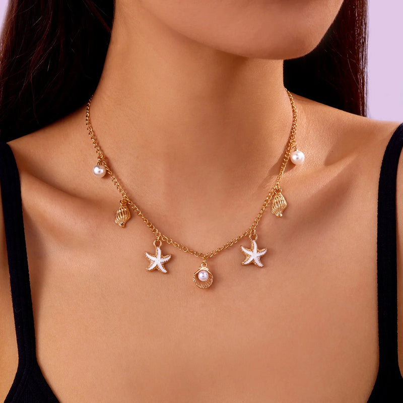 Femme portant un collier bohème doré avec étoiles de mer et coquillages blancs, sur fond violet