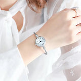 Montre bracelet argentée avec cadran blanc à chiffres romains portée au poignet