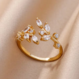 Bague dorée avec motif feuilles et zircons blancs sur fond beige