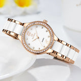 Montre quartz femme tendance bracelet bicolore blanc et doré rose, cadran blanc index 12 et strass, posée sur une surface blanche