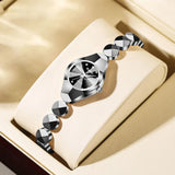 Montre femme bracelet acier noir et argenté sur présentoir, avec cadran discret