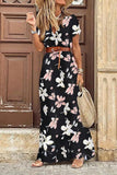 Femme portant une robe longue noire à motifs de grandes fleurs roses et blanches, ceinture marron et chapeau de paille