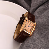 Gros plan montre carrée rétro femme bracelet cuir noir cadran blanc chiffres romains, aiguilles bleues