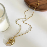 Gros plan sur un collier doré avec pendentif coquillage