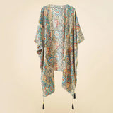 Kimono de plage bohème floral avec glands, suspendu sur un fond neutre