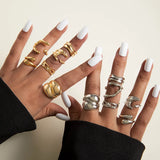 Set de 6 bagues irrégulières dorées et argentées sur les mains avec ongles blancs