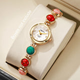 Montre femme bracelet perles colorées avec cadran blanc, posée sur un coussin, sans boîte