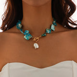 Collier bohème avec perles carrées bleues et pendentif perle baroque sur un décolleté blanc