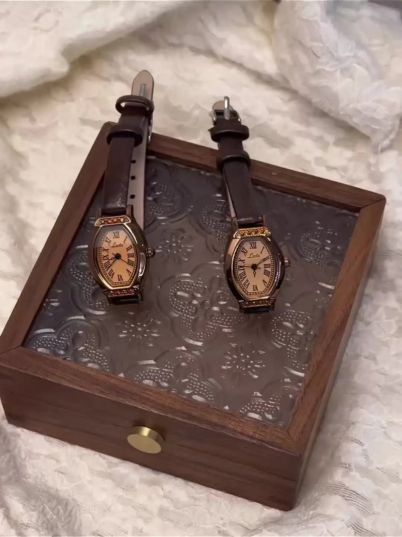 Deux montres vintage à bracelet cuir marron et cadran tonneau sur un plateau en bois