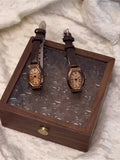 Deux montres vintage à bracelet cuir marron et cadran tonneau sur un plateau en bois