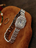 Montre femme dorée en gros plan, cadran nacré et aiguilles bleues