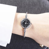 Montre bracelet rose doré avec cadran rose à chiffres arabes portée au poignet