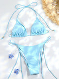 Bikini triangle bleu ciel pastel, bas micro string réglable, sur fond blanc avec fleurs bleues et chapeau de paille