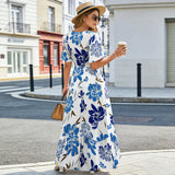 Femme de dos en robe longue fleurie bleue et grise, manches à volants, marchant dans la rue