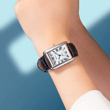 Montre carrée rétro femme bracelet cuir noir cadran blanc chiffres romains portée au poignet