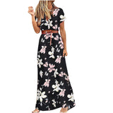 Robe longue fleurie noire portée par une femme sans accessoires sur fond blanc