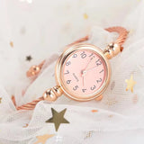 Gros plan du cadran d'une montre bracelet rose doré avec chiffres arabes