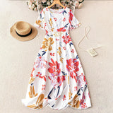 Robe longue fleurie colorée à plat, motifs rouge, orange, bleu sur fond blanc, avec chapeau de paille et collier