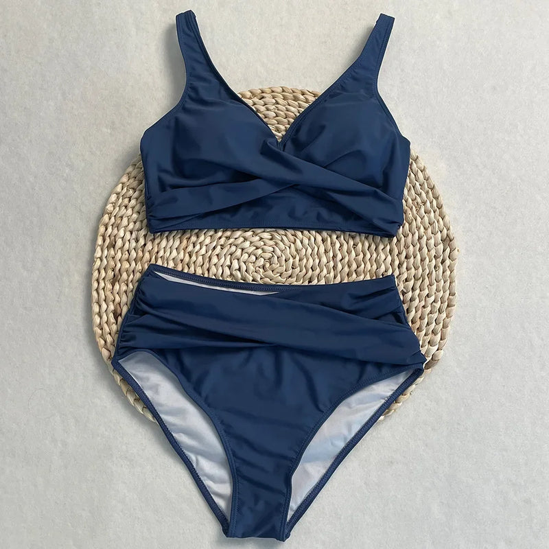 Maillot de bain deux pièces taille haute bleu marine, haut croisé et culotte drapée sur fond clair